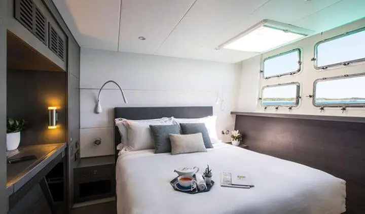 Double bed in a cabin with light walls, pillows, and window