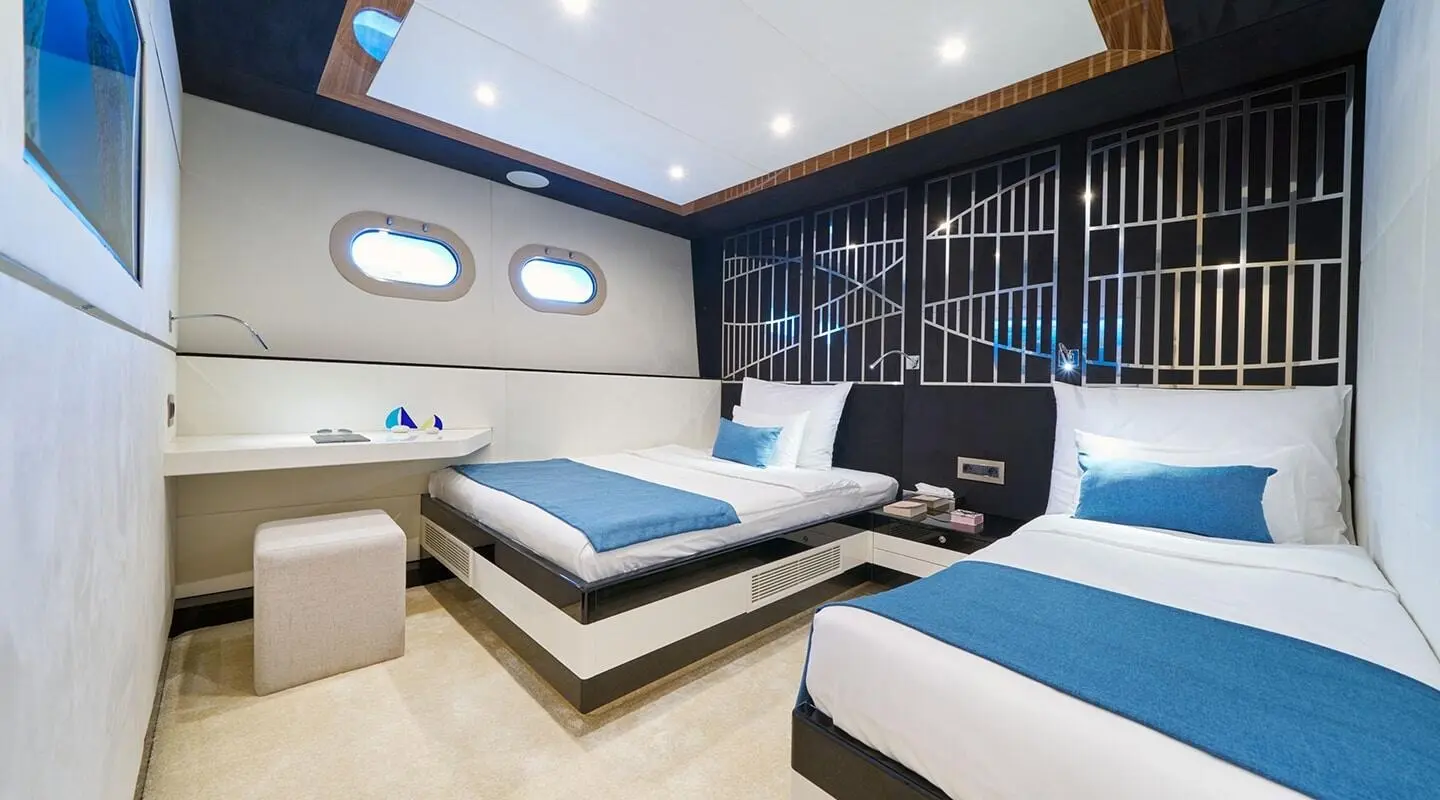 Luxurious Acapella yacht interior with blue and white berths and porthole windows