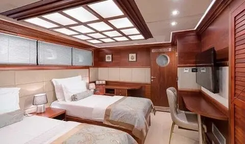 Twin cabin on Lady Gita yacht with two single beds, wood paneling, and porthole windows