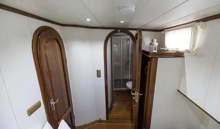 A yacht cabin with wooden doors, narrow hallway, and overhead ceiling light