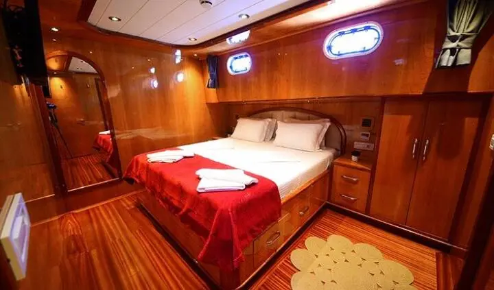 Cozy cabin bedroom on Maya with bed, red bed runner, wood panels