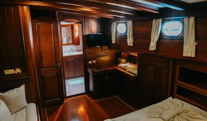 Luxurious yacht master cabin with king bed, wood paneling, and ensuite bathroom