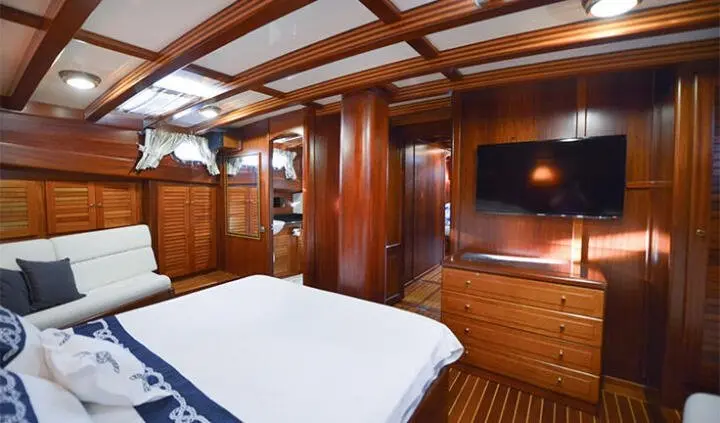 Master cabin with king bed, wood paneling, built-in wardrobes, and ensuite