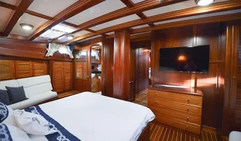 Master cabin with king bed, wood paneling, built-in wardrobes, and ensuite