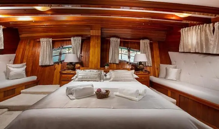 Spacious yacht cabin with king bed, crisp white linens and wood paneling