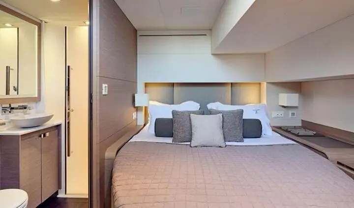 Christal Mio yacht cabin interior with king bed, plush pillows, and ensuite vanity