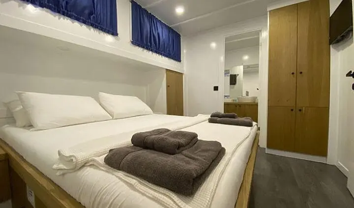 Master cabin with king bed, white linens, brown throws, ensuite area visible