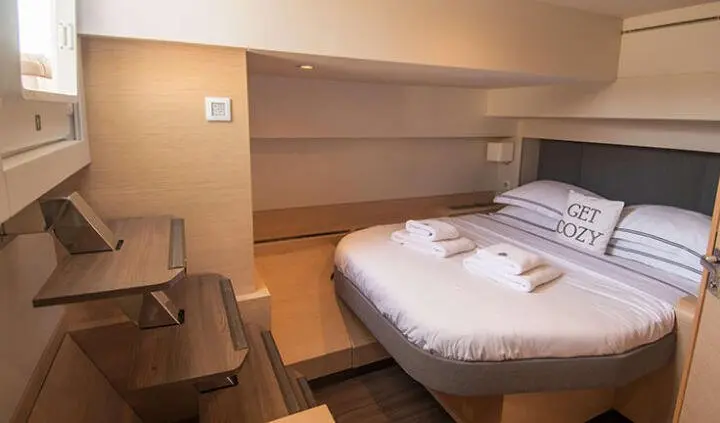 Serenissima master cabin with neatly made bed and built-in wooden shelves