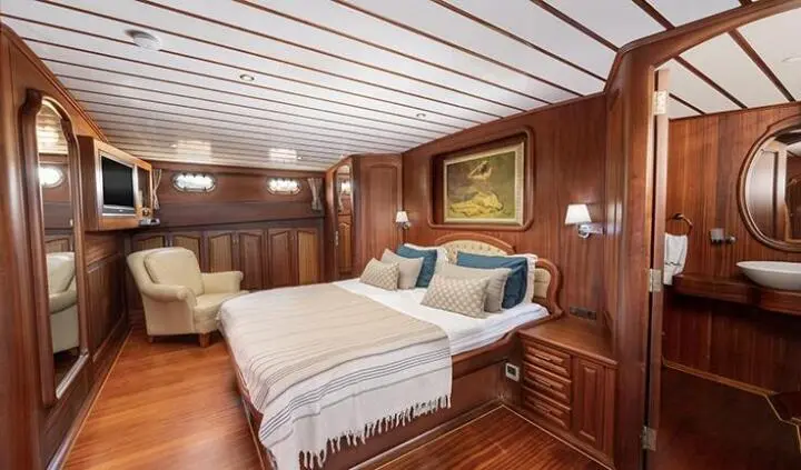 Luxurious yacht cabin with double bed, wooden panels, and ensuite bathroom door