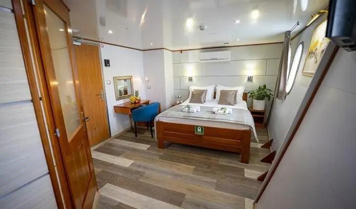Master cabin aboard Karizma with king bed, ensuite, wood accents, bedside lamps
