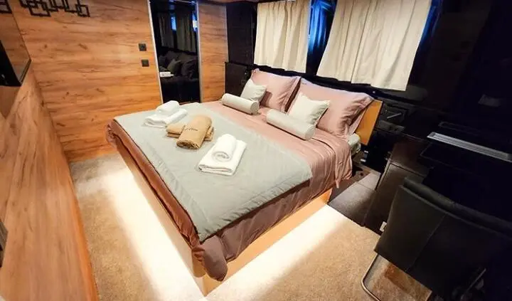 Master cabin with king bed, beige linens, wood accents, and ensuite doorway