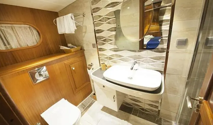 Master cabin with king bed, ensuite, wood cabinetry, stone walls, and porthole light