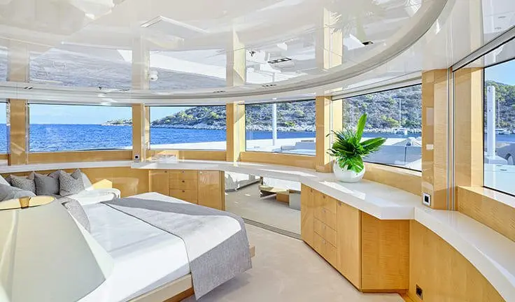 Master cabin with king bed, wood cabinetry, portholes, and seating overlooking ocean