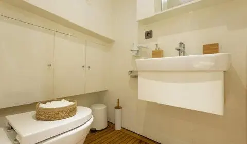 Compact yacht cabin with bed, ensuite bathroom, sink, and storage shelves