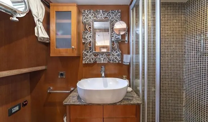 Arabella yacht cabin ensuite with sink, mirror, wooden cabinetry and decorative tiling