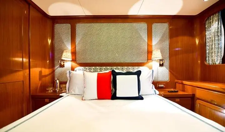 Tamarita cabin with queen bed and pillows, warm wood paneling and window