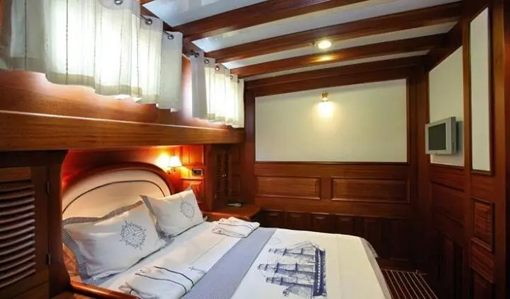 Master cabin with king bed, wood-paneled walls, and porthole lights
