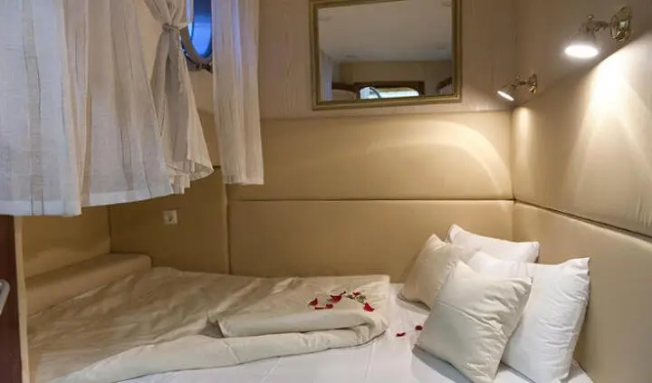 Cozy cabin bedroom aboard Aborda with bed, pillows, and porthole view