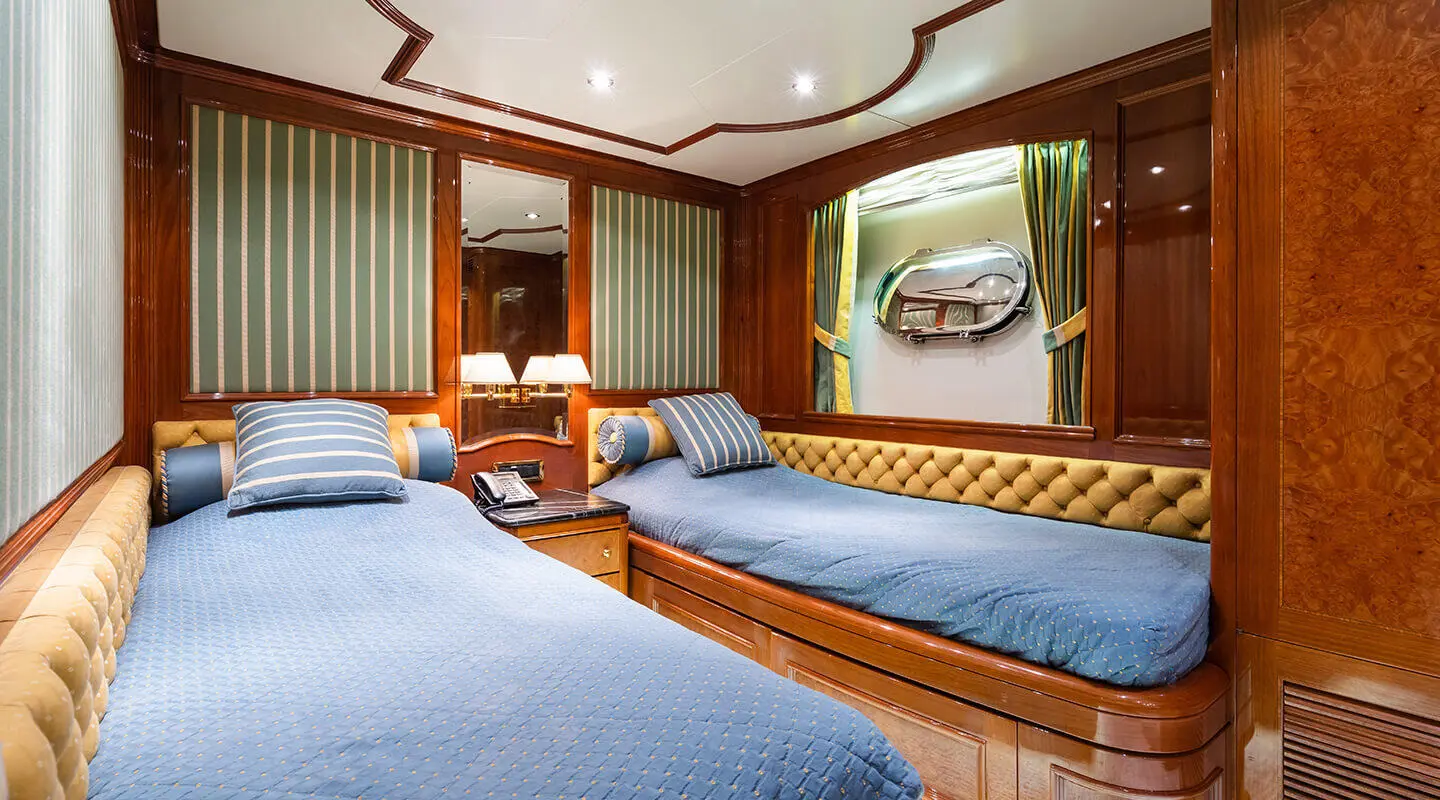 Two blue-covered lounge beds on a luxury yacht deck with wooden panels