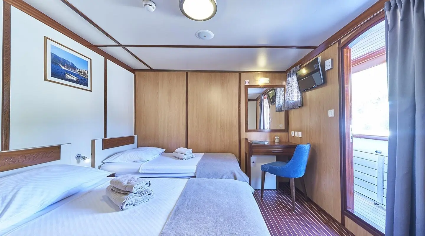 Amorena yacht deck area with bed, wood cabinets, and seating under blue canopy