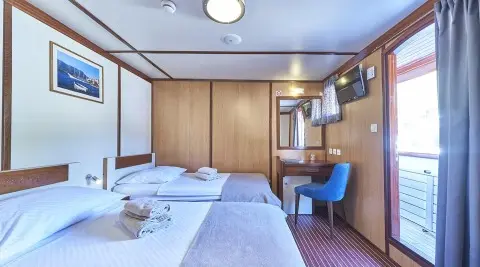 Amorena yacht deck area with bed, wood cabinets, and seating under blue canopy