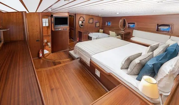 Master cabin with king bed, wood paneling, bedside lamps, ensuite doorway