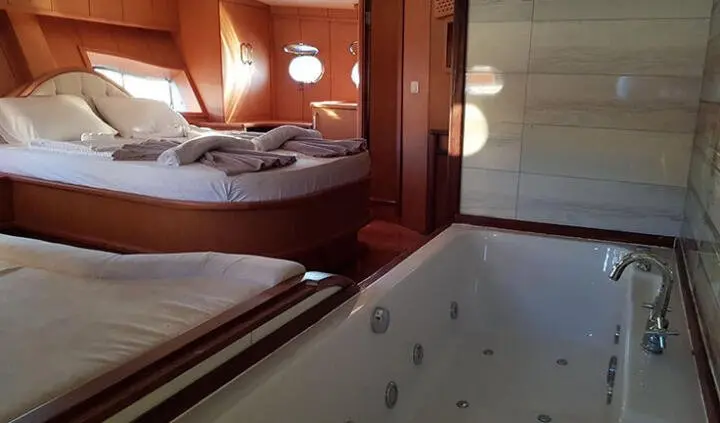 Blu Dream cabin interior with plush bed, wood paneling, and a large soaking tub onboard