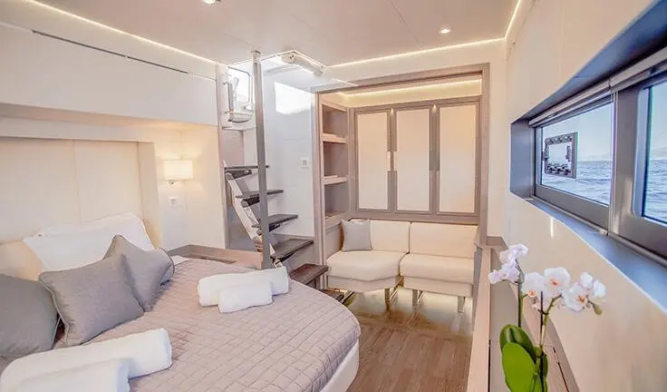 Master cabin with king bed, ensuite, neutral tones, wood accents, compact seating area