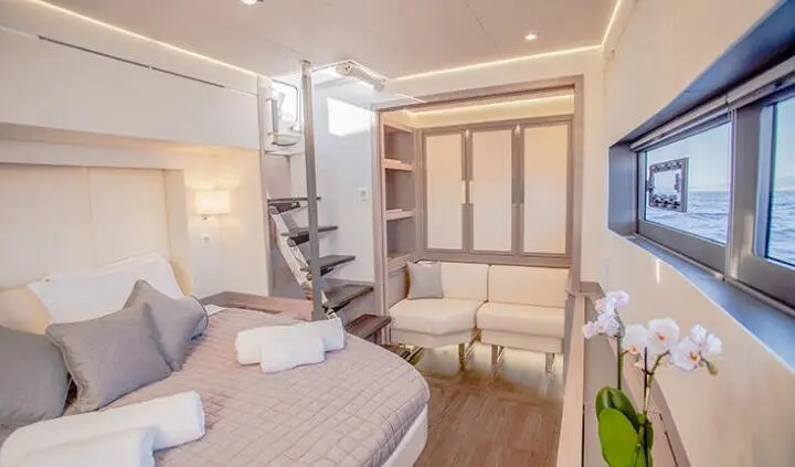 Master cabin with king bed, ensuite, neutral tones, wood accents, compact seating area