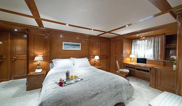 Aquila cabin with a round bed, white linens, wooden paneling and bedside lamps