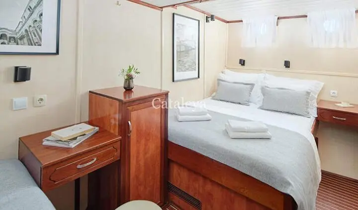 Cabin aboard Cataleya yacht with double bed, wood furniture, framed art