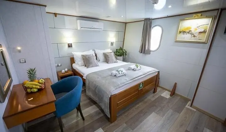 Karizma cabin with queen bed, reading lamps, windows, and blue chair