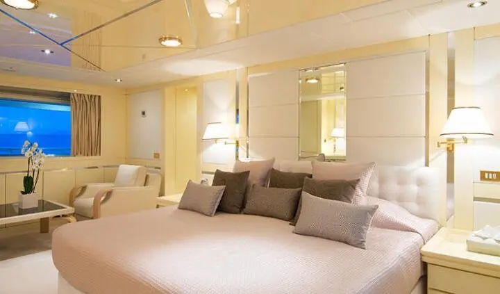 Master cabin with a large bed, beige walls, and multiple pillows on board yacht O'Natalina