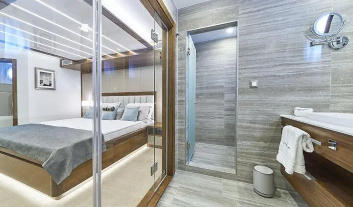 Corsario cabin interior with a luxurious bed, glass partition, and modern ensuite bathroom