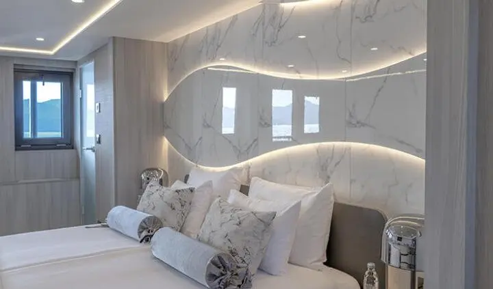 Master cabin with king bed, plush pillows, and ensuite door on yacht Freedom