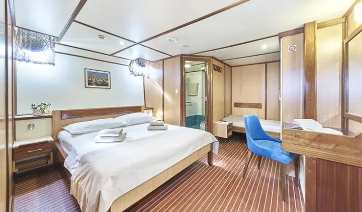 Amorena yacht cabin with a large bed, wood tones, and seating area