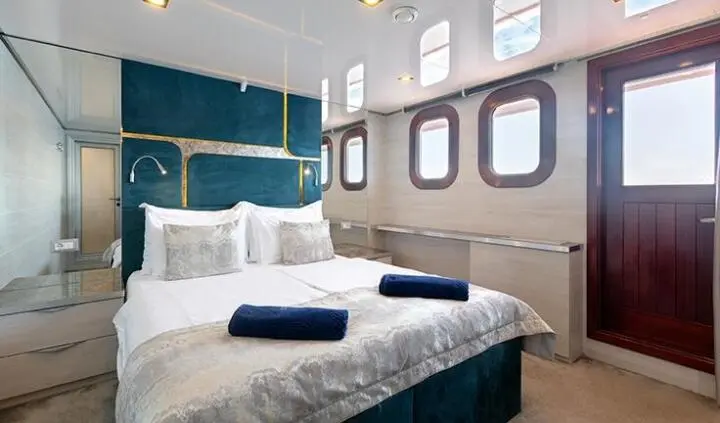 Master cabin with king bed, white linens, ensuite door, porthole windows