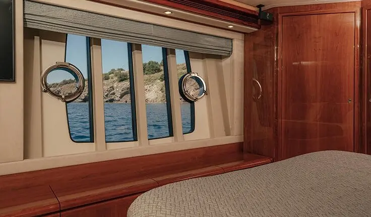 Wood-paneled bathroom aboard Lidia yacht with a porthole and towel ring