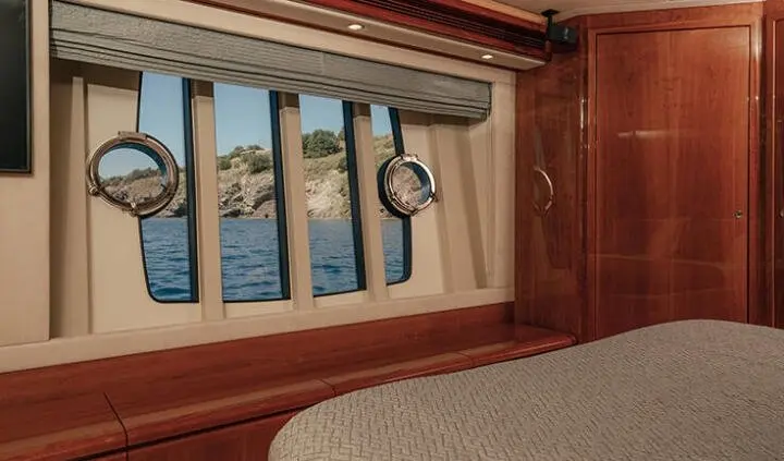 Wood-paneled bathroom aboard Lidia yacht with a porthole and towel ring