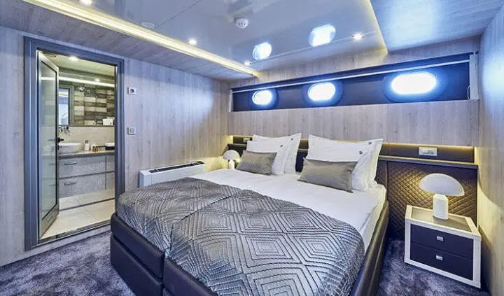 Dalmatino yacht cabin with double bed, cushions, wood paneling, and soft lighting