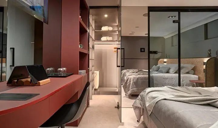 Bedroom aboard Anetta yacht with twin beds, wood accents, and a doorway to the hallway