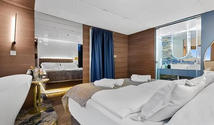 Master cabin with king bed, white linens, wooden panels, and ensuite door