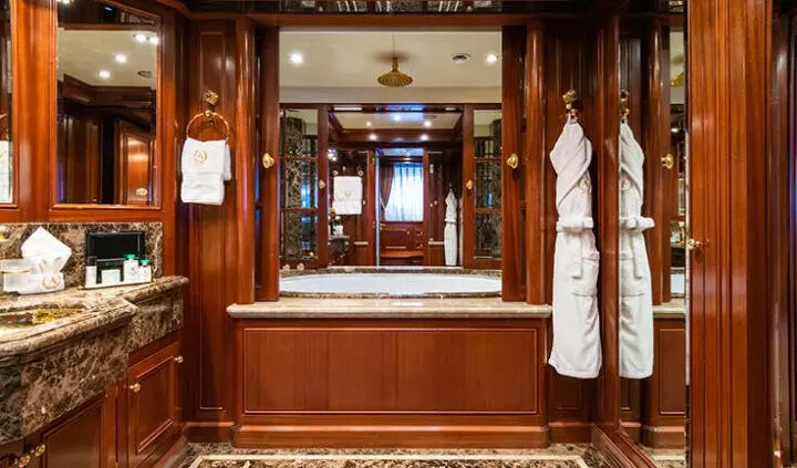 View of a teak wood cabin interior with bed, mirror, and cabinetry