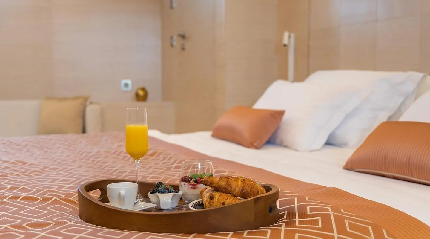 Luxurious yacht Love Story bedroom with breakfast tray on bed and orange juice
