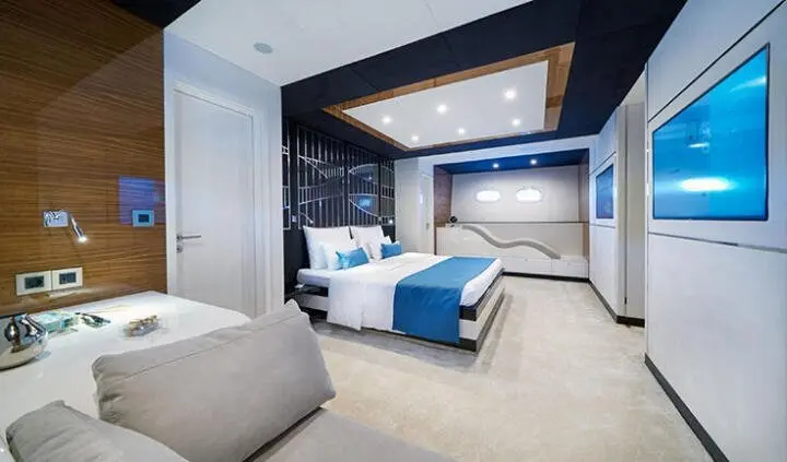 Master cabin with king bed, blue and white bedding, ensuite doorway on left