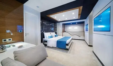Master cabin with king bed, blue and white bedding, ensuite doorway on left