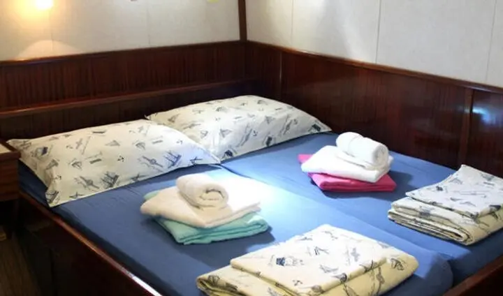 Twin bed cabin with pillows and folded towels on blue bedding