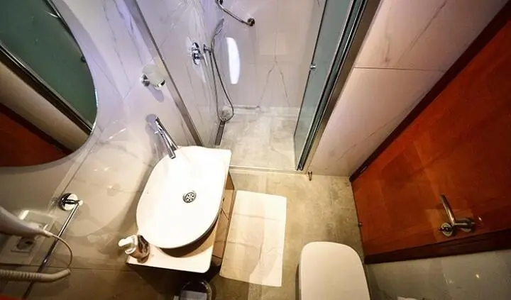 Bathroom on Maya yacht with shower, sink, and beige tile flooring