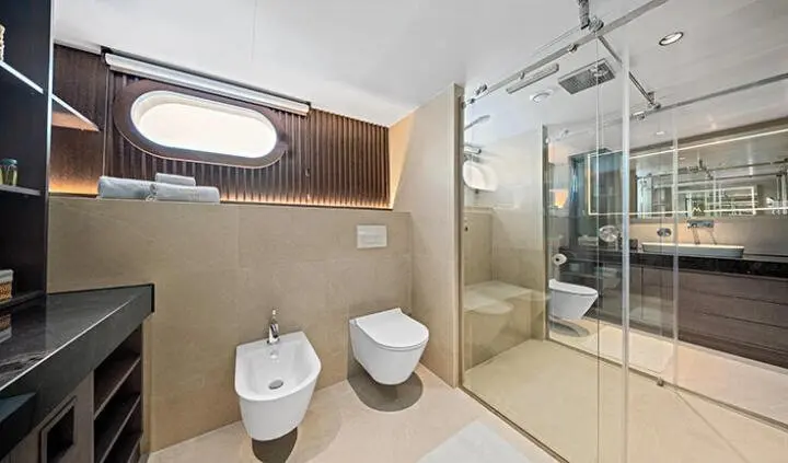 Master cabin with king bed, ensuite, neutral beige decor, window, and glass shower