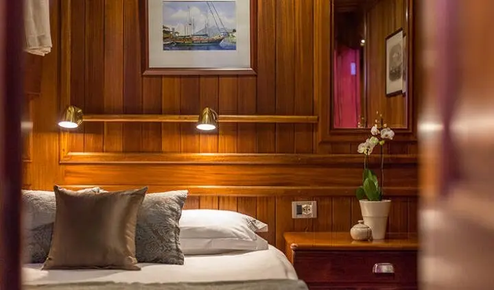 Master cabin with king bed, wood-paneled walls, nightstands and ensuite door